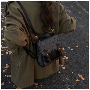 Outdoor shot of a small vintage backpack with grey polka dots and black leather accents
