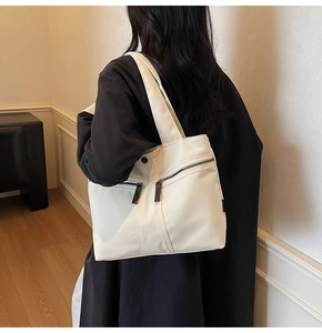 Detail view of cream canvas tote bag featuring double diagonal front zipper pockets