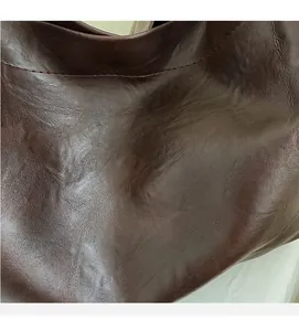 Close-up of the soft dark brown lychee-patterned leather texture and fine stitching detail