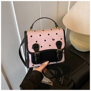 Detail of pink polka dot canvas backpack with black leather trim and golden metal buckles