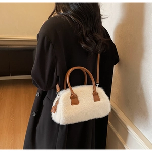 Close-up of fluffy white faux fur crossbody bag with brown PU straps on a black wool coat