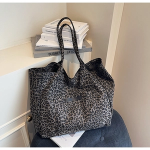 Detail of leopard print tote bag on a blue corduroy chair with minimalist art books