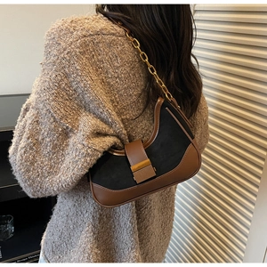 Detail of vintage patchwork baguette bag with gold chain and metal buckle on knits