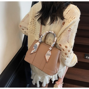 Brown leather bucket bag with silk scarf handle and strap shown on a staircase