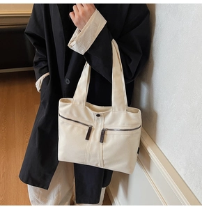 Detail shot of a large canvas tote bag with functional front zippers and strap details