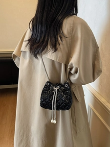 Detail shot of black quilted bucket bag featuring large pearl charms and silver chain strap