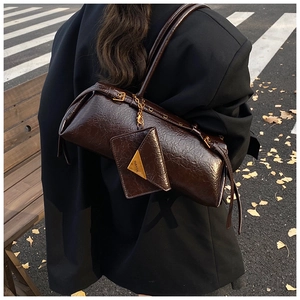 Close-up of retro brown oil-wax leather cylinder bag with triangle coin pouch detail