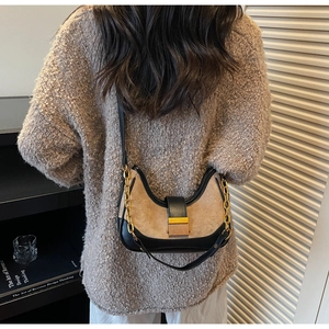 Model wearing a vintage crescent shoulder bag with leather stitching and gold buckle