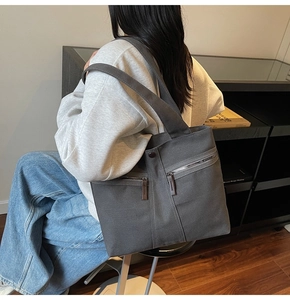 Detail of grey canvas tote bag featuring double front zip pockets and leather pulls