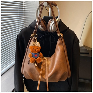 Brown retro crescent bag detail with plush bear charm and sleek tassel zipper