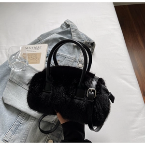 Detail of black faux fur tote bag with leather handles and strap in cozy lifestyle setting
