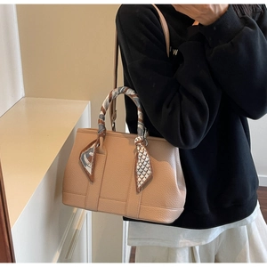 Detail of beige lychee leather bucket bag with elegant silk scarf wrapped handle