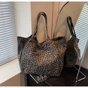 Detail of leopard print tote bag with outer pocket on a desk next to a mirror