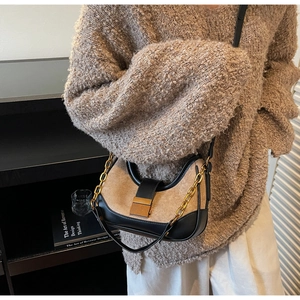 Détail du sac hobo en daim beige et cuir noir avec une chaîne en métal dorée
