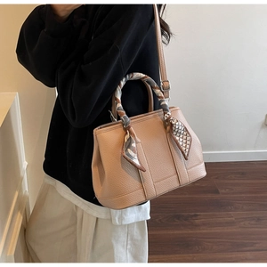 Detail of light brown lychee grain leather handbag with silk scarf wrapped handle