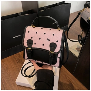 Detailed close-up of pink polka dot handbag with black bow and gold hardware accents