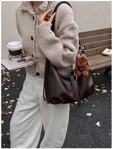 Detail of dark brown leather dumpling bag with cute bear charm in a street style setting