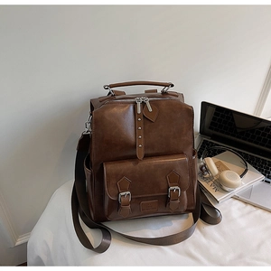 Close-up of vintage brown leather backpack with silver rivets and multi-pocket detail