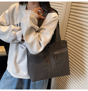 Detail view of charcoal canvas tote bag featuring double front zipper pockets and leather pulls