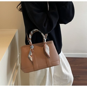 Brown lychee leather bucket bag detail with floral silk scarf wrapped on the handle