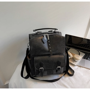 Detail of black vintage leather backpack showing top handle and leaf-shaped zipper charms