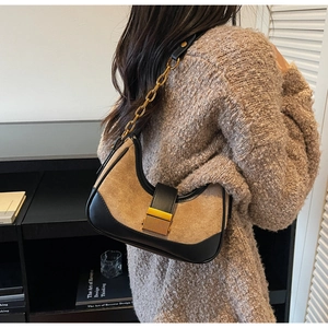 Gros plan du sac en daim kaki et cuir noir avec une chaîne dorée et une boucle en métal