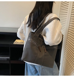 Detail of grey canvas tote bag with metal zipper pocket shown in a lifestyle setting