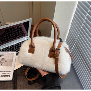 Close-up of white fluffy Boston bag with brown leather handles and silver hardware detail