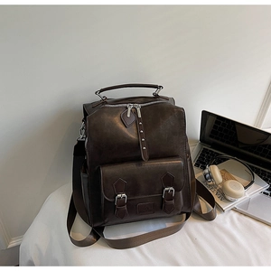 Detail of vintage dark brown faux leather backpack with double buckle front pocket design