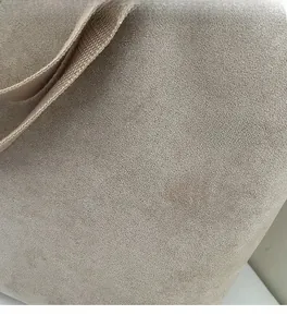 Detailed macro shot of the beige canvas bag featuring soft textured fabric and woven handles