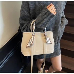 Detail of beige pebble leather handbag with geometric silk scarf on handle and strap