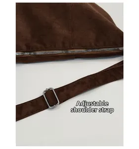 Detailed close-up of adjustable shoulder strap and silver zipper on brown suede bag