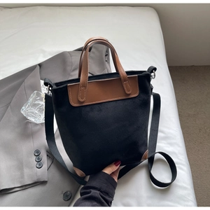 Close-up of black canvas tote bag with brown leather handles and adjustable shoulder strap