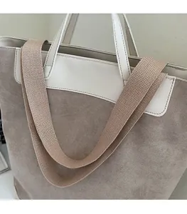 Detail of light brown suede tote bag featuring a white leather trim and wide knit strap