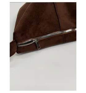 Close-up of smooth silver zipper and stitching on dark brown suede shoulder bag