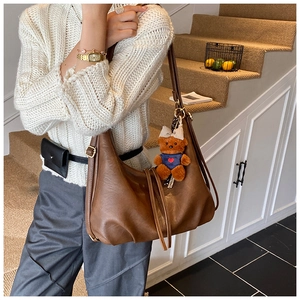 Close-up of vintage brown slouchy shoulder bag with pleats and cute bear charm detail
