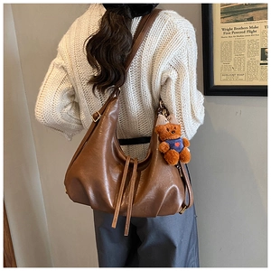Retro brown leather hobo bag with teddy bear pendant shown on model's shoulder
