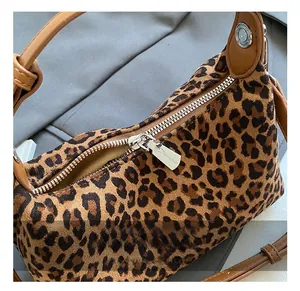 Detailed close-up of the leopard print handbag showing the silver metal zipper hardware