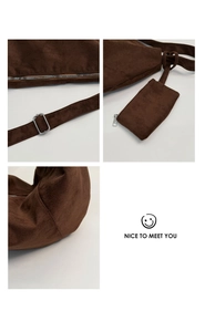Detail view of dark brown suede shoulder bag featuring silver metal zippers and stitching