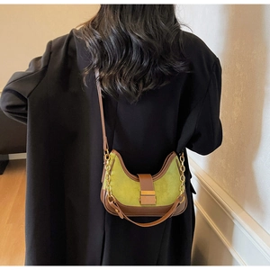 Sac demi-lune en daim vert avec chaîne en métal porté par un mannequin
