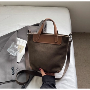 Detail of dark brown canvas bucket bag showing leather handles and textured strap