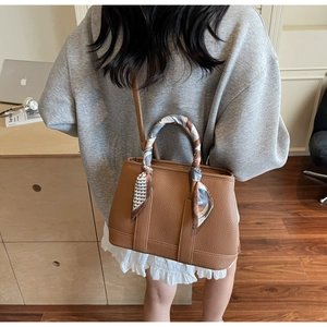 Detailed shot of brown lychee grain leather tote bag with a floral scarf handle decoration