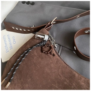 Détail d'un sac bandoulière en daim marron avec pendentif grain de café et cordon tressé