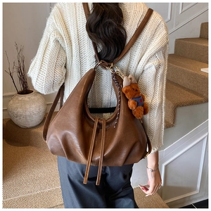 Brown leather hobo bag with pleated details and a cute teddy bear charm on the strap
