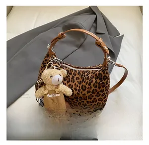 Detailed view of leopard print fabric texture and premium brown leather handle on the bag