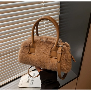 Detail view of brown faux fur handbag with leather handle and metal buckle strap