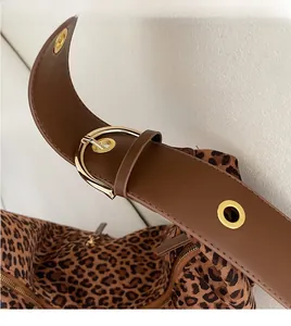 Close-up of leopard print tote with adjustable brown leather strap and gold buckle