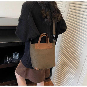 Detailed view of a tan canvas tote bag with brown leather handles worn by a model