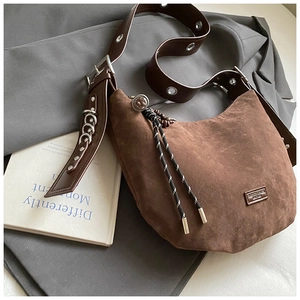 Détail du sac hobo en daim marron avec bandoulière en cuir et œillets métalliques