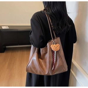 Brown vintage leather tote bag with bear charm shown on model for size perspective